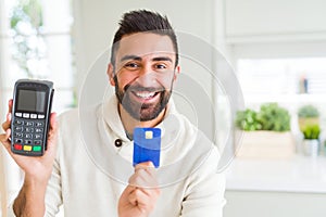 Business man smiling and holding point of sale terminal and credit card, contacless transaction