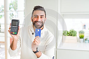 Business man smiling and holding point of sale terminal and credit card, contacless transaction