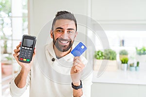 Business man smiling and holding point of sale terminal and credit card, contacless transaction