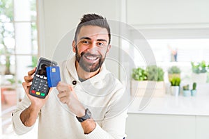 Business man smiling and holding point of sale terminal and credit card, contacless transaction