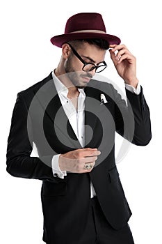 Business man standing and fixing hat while looking down