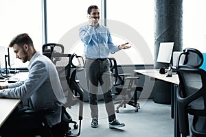 Business man standing inside office building and using cell phone.