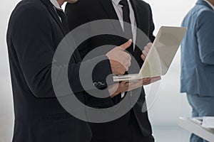 Business man standing and showing trumps up to his colleague aft photo