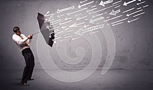 Business man standing with umbrella and drawn arrows hitting him