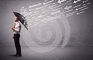 Business man standing with umbrella and drawn arrows hitting him