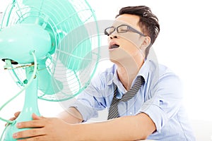 Uomo d'affari la sofferenza di una calda estate di calore con ventilatori in ufficio.