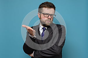 Business man in a suit is bewildered, he strictly looks at the camera and makes a questioning gesture with hand.