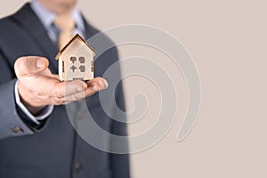 Business man in suit having miniature house on palm of his hand - Business mortgage, property loan, house insurance, business