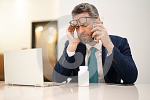 Business man in suit with headache. Tired businessman is working overtime and has headache. Man with laptop at workplace