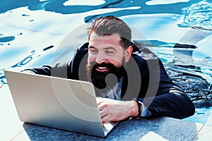 Business man in suit with laptop on swimming pool. Funny businessman relaxing with laptop.