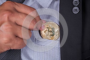 Business man in suit pick bitcoin in to pocket