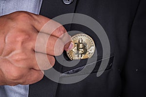 Business man in suit pick bitcoin in to pocket