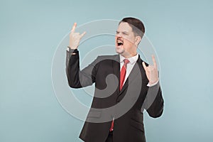 Business man in suit showing rock sign and roar