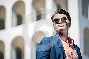 Business man with sunglasses. He blue jacket and shirt. In the background a building