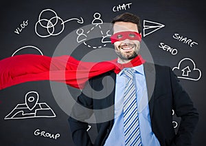 Business man superhero with hands on hips against navy chalkboard with white business doodles