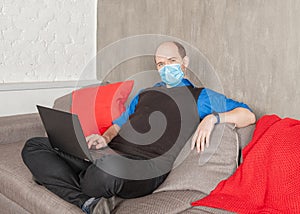 Business man in surgical medical virus protection mask working at home