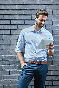 Business man, tablet and research, reading email or info online on a wall background in city. Smile, digital technology