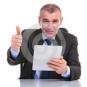 Business man with tablet shows the thumb up sign