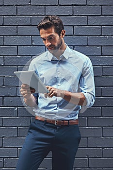 Business man, tablet and web research, reading email or info online on a wall background in city. Serious, digital tech