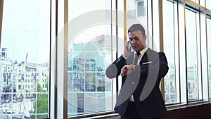 Business man takes a phone call and looks at his wrist watch