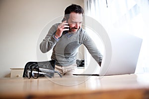 Business man talking on mobile phone and looking at computer