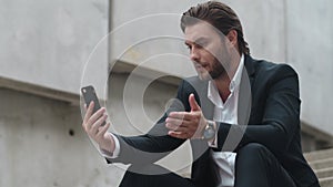 Business man talking online with client on street. Male manager using smartphone