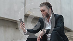 Business man talking online with client on street. Male manager using smartphone