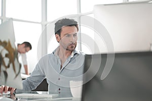 Business man talking to a colleague sitting at his Desk