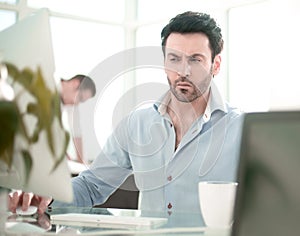 Business man talking to a colleague sitting at his Desk