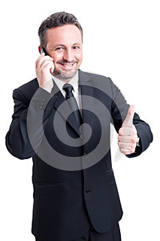 Business man talks on the phone and shows thumb up