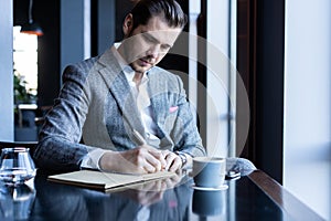 Business man thinks looks out the window, cafe, documents, cup of coffee