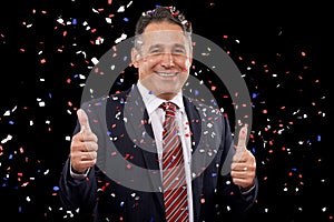 Business man, thumbs up and confetti for celebration, success and winning, thank you or support in election in studio