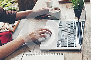 Business man typing laptop and holding coffee cup on wood table.