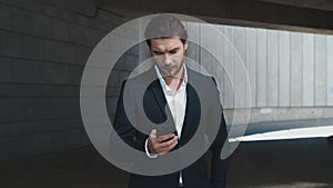 Business man typing message on smartphone outdoors. Man using cellphone