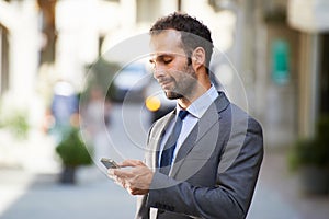 Business man typing sms on mobile phone in street