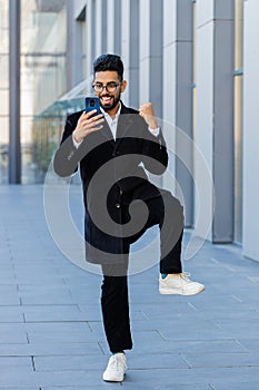 Business man use mobile smartphone celebrating win good message news outdoors in urban city street