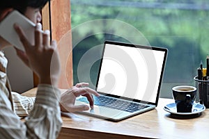 Business man using computer laptop and talking on mobile phone while sitting in office.