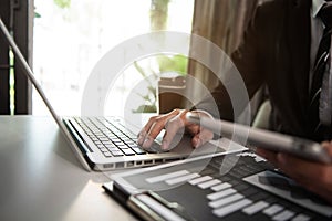 Business man using digital tablet analyzes business data, busy working on laptop computer.