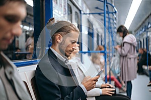 business man using his smartphone while sitting in the train subway.