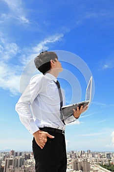 Business man using laptop and look to blue sky