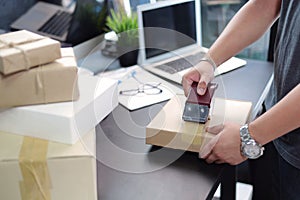 Business man using Metal Tape Dispenser and packing a parcel box on black desk in home office .selective focus.product packaging