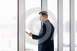 Business man using mobile phone app in airport. Young business professional man texting smartphone walking inside office