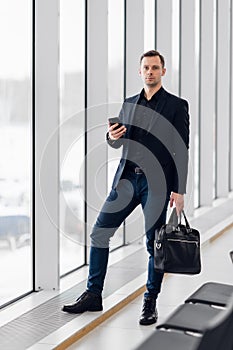 Business man using mobile phone app in airport. Young business professional man texting smartphone walking inside office