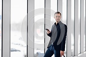 Business man using mobile phone app in airport. Young business professional man texting smartphone walking inside office