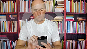 Business man using mobile phone in home office on bookcase background