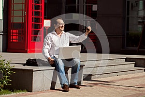 Business man using mobile phone red classic English telephone bo