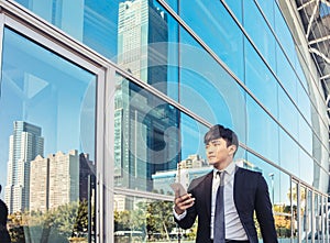 Business man using mobile phone and standing in front of  office building