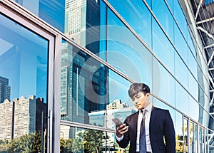 Business man using mobile phone and standing in front of  office building