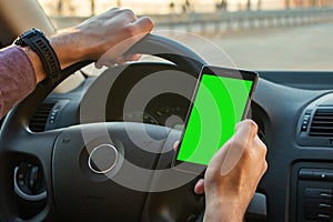 Business man using mobile smart phone, checking address location via navigator application, driving a car. Driver hand holding and