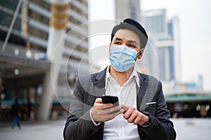 Business man using a smartphone and wearing medical mask during coronavirus covid-19 pandemic